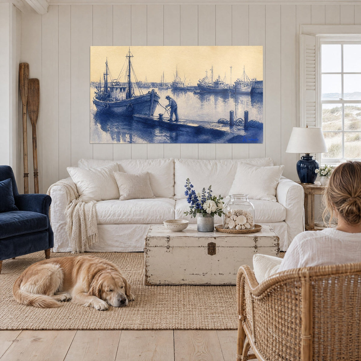 Tableau pêcheur amarrant son chalutier bleu sur un ciel jaune sable, reflets dans l'eau, au-dessus d'un canapé dans un salon lumineux