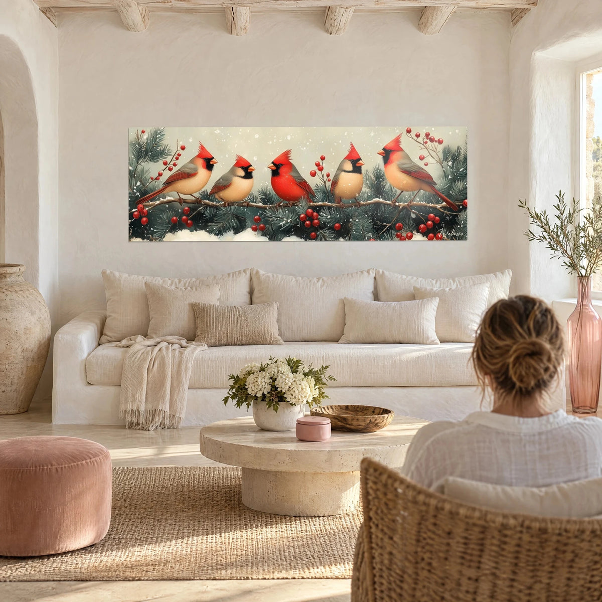 Wall art of red and beige cardinals perched on a snowy branch, scarlet berries, above a sofa in a bright living room