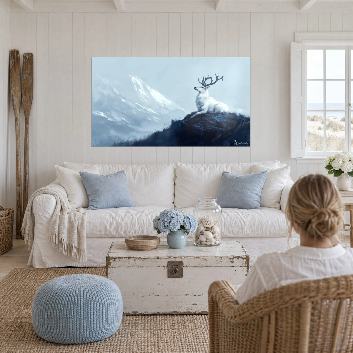 Tableau cerf blanc couché sur un rocher bleu nuit, montagne givrée en brume, au-dessus d'un canapé dans un salon lumineux