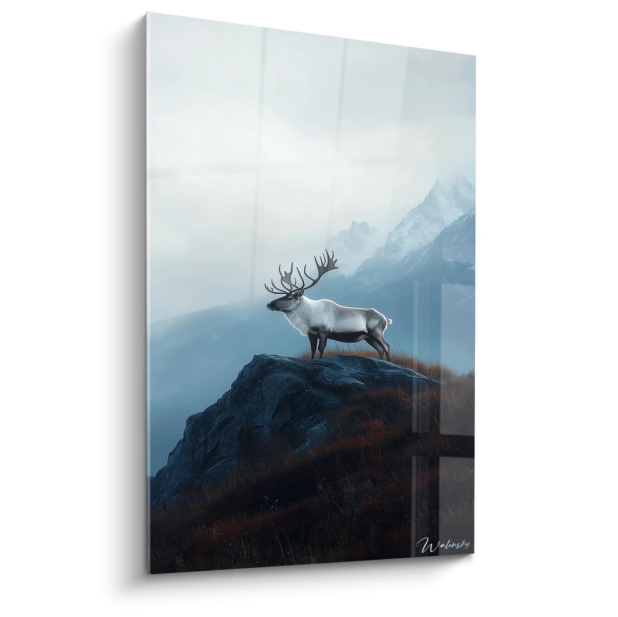 Un tableau artistique abstrait présentant un caribou majestueux au pelage gris-blanc, debout sur un rocher sombre, avec en arrière-plan des montagnes brumeuses bleutées et une végétation automnale rousse sur les pentes.
