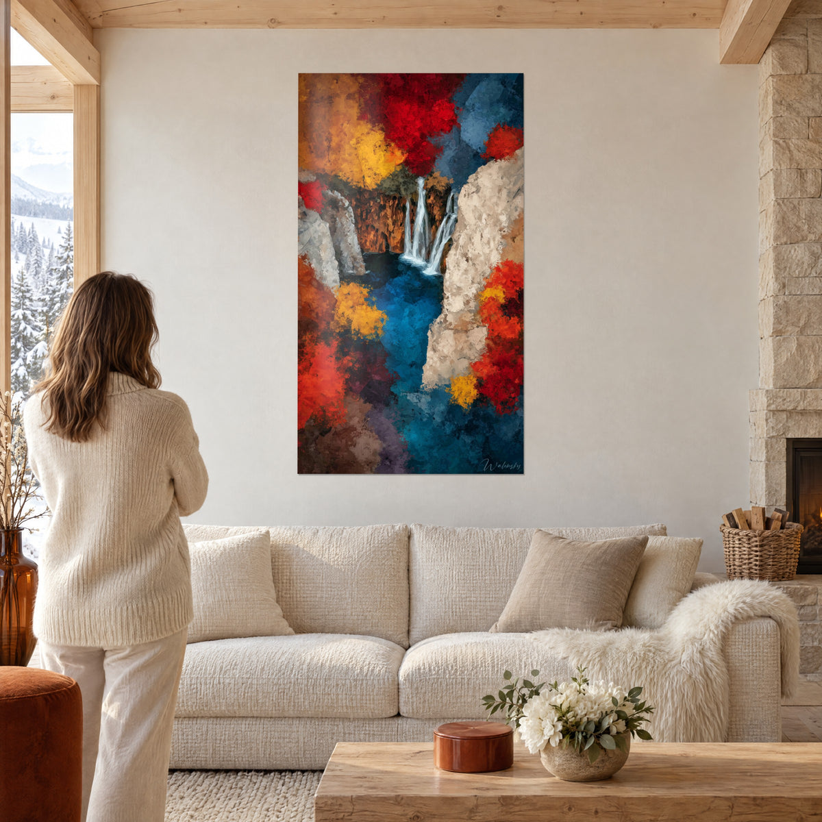 Cuadro cascada en pintura al óleo, rojo vivo y amarillo dorado, dos saltos sobre un acantilado ocre, una mujer de espaldas encima de un sofá en un salón luminoso
