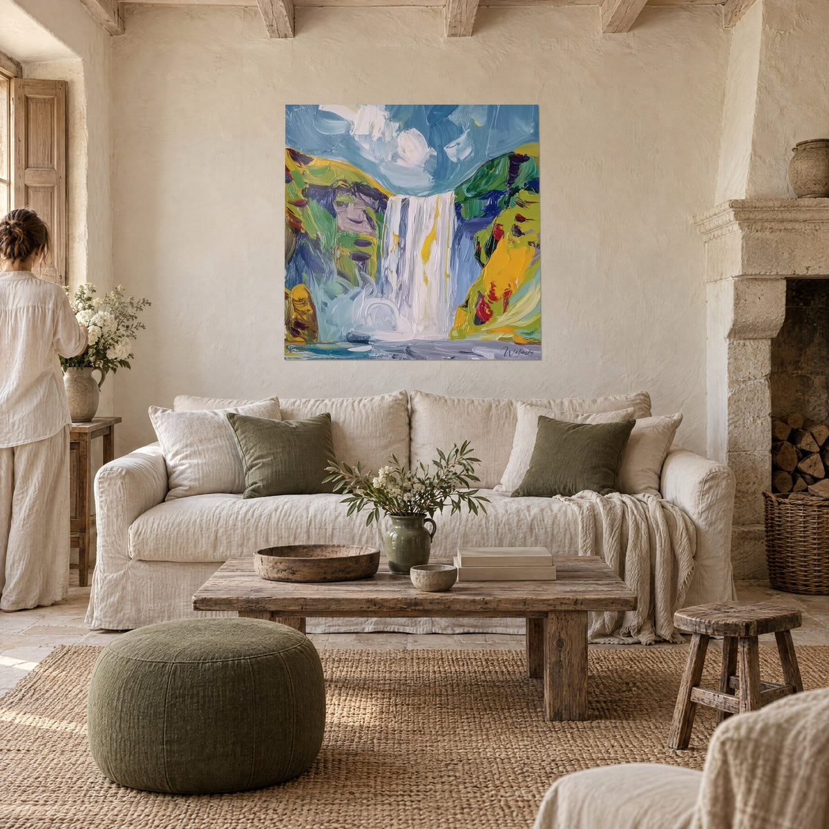 Gemälde Wasserfall weiß, eingerahmt von grünen und gelben Hügeln, blauer Himmel, zwei Personen von hinten, über einem Sofa in einem hellen Wohnzimmer