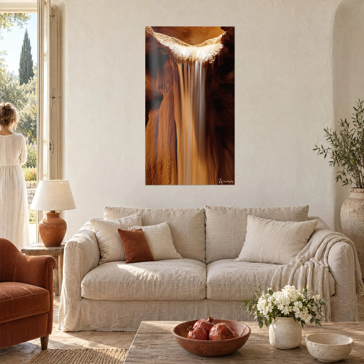 Tableau chute d'eau laiteuse dans une grotte d'ocre et de cuivre, deux silhouettes de dos, au-dessus d'un canapé dans un salon lumineux