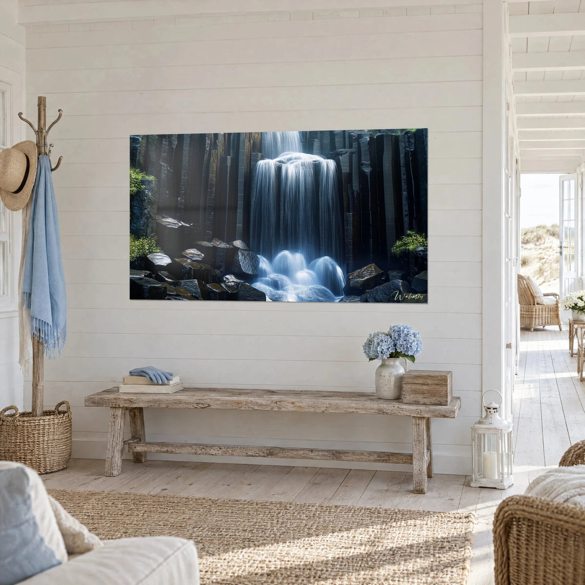 Tableau chute d'eau en pose longue, voile blanc et bleu sur colonnes de basalte sombre, banc en bois clair, vue de trois-quarts
