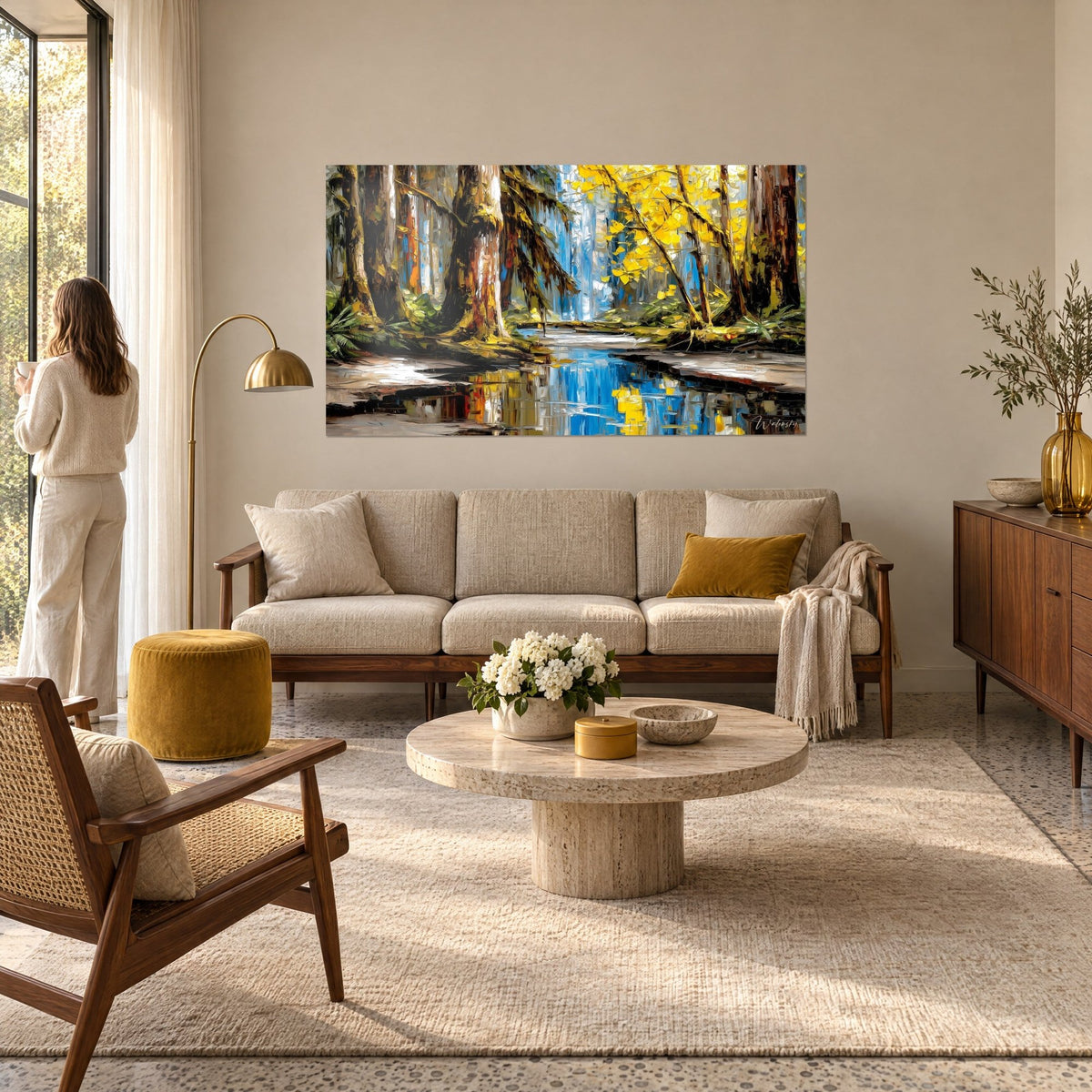 Tableau forêt tropicale aux troncs moussus, feuillage jaune d'or et mare bleu cobalt, regardé par une femme de dos au-dessus d'un canapé dans un salon lumineux