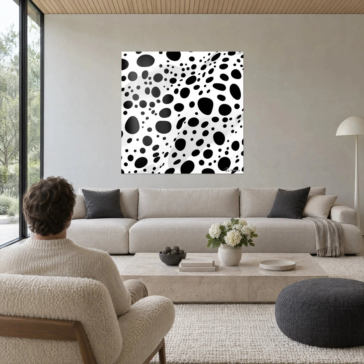 Gemälde mit schwarzen ovalen Flecken auf weißem Grund, graue Schattenwellen, Mann von hinten, über einem Sofa in einem hellen Wohnzimmer