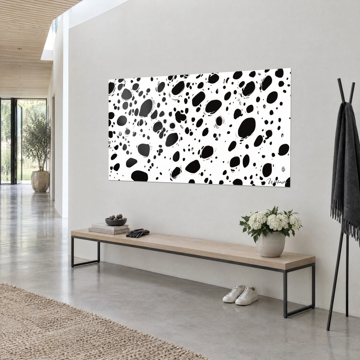 Cuadro con motivo abstracto de dálmata, grandes óvalos negros perfilados con trazos blancos, sobre pared gris claro, vista de tres cuartos