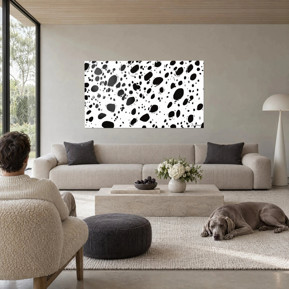Tableau taches d'encre noires sur fond blanc, pois irréguliers et éclaboussures, au-dessus d'un canapé dans un salon lumineux