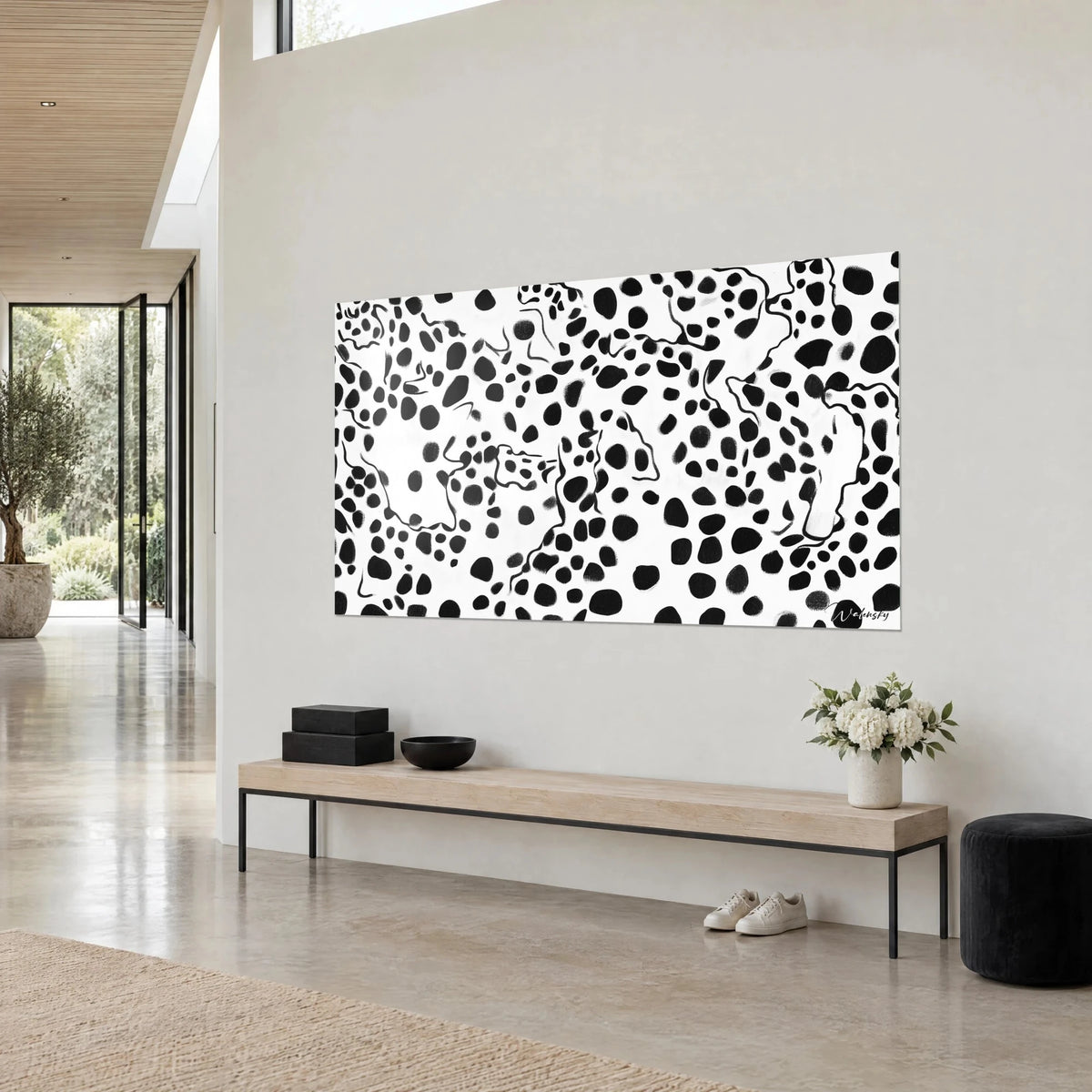 Quadro con manto di leopardo stilizzato, ovali neri e contorni sottili su bianco, visto di scorcio, sopra una panca in legno chiaro