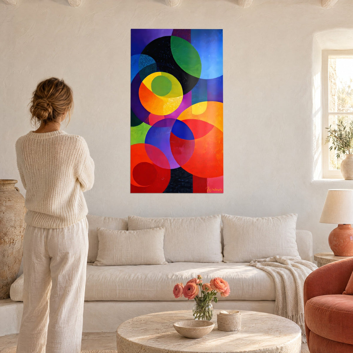 Tableau cercles superposés orange et bleu roi, noir profond, une femme de dos, au-dessus d'un canapé dans un salon lumineux