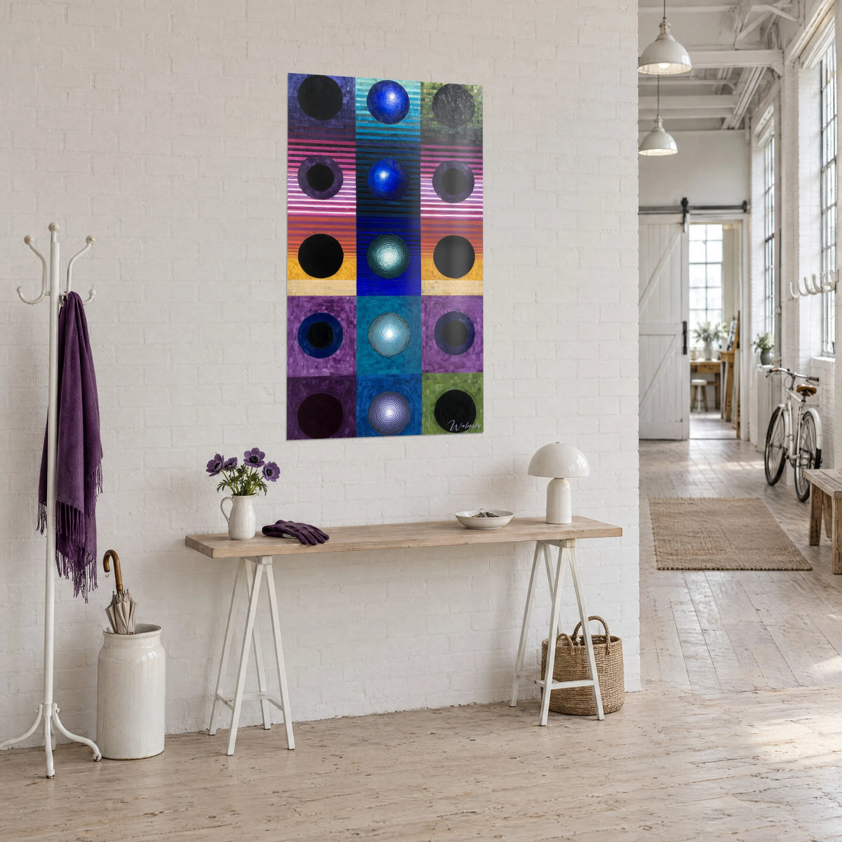 Cuadro tríptico de discos oscuros sobre franjas magenta, índigo y ocre, vista de tres cuartos junto a una consola del loft de artista