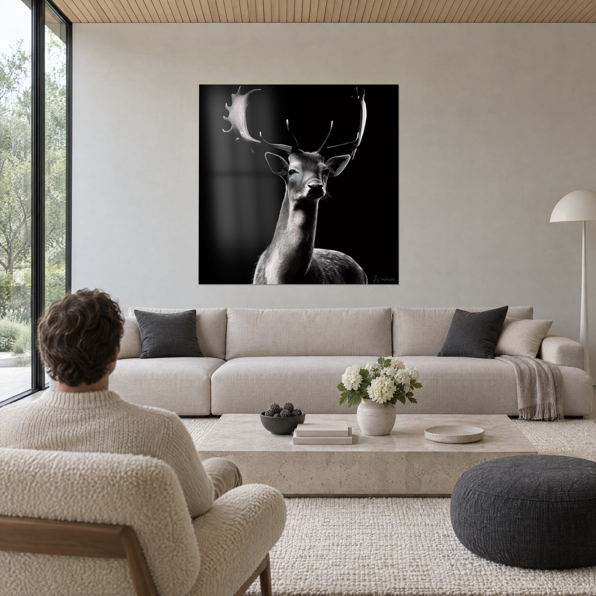 Gemälde Hirsch-Damhirsch mit handförmigem Geweih, silbergraues Fell auf schwarzem Hintergrund, ein Mann von hinten über einem Sofa in einem hellen Wohnzimmer