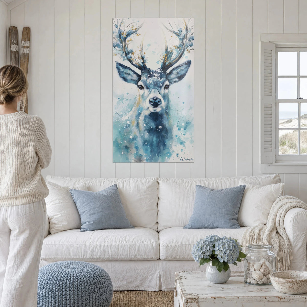 Wall art stag with frost-tipped antlers in gold, glacier blue and snow white, above a sofa in a bright living room