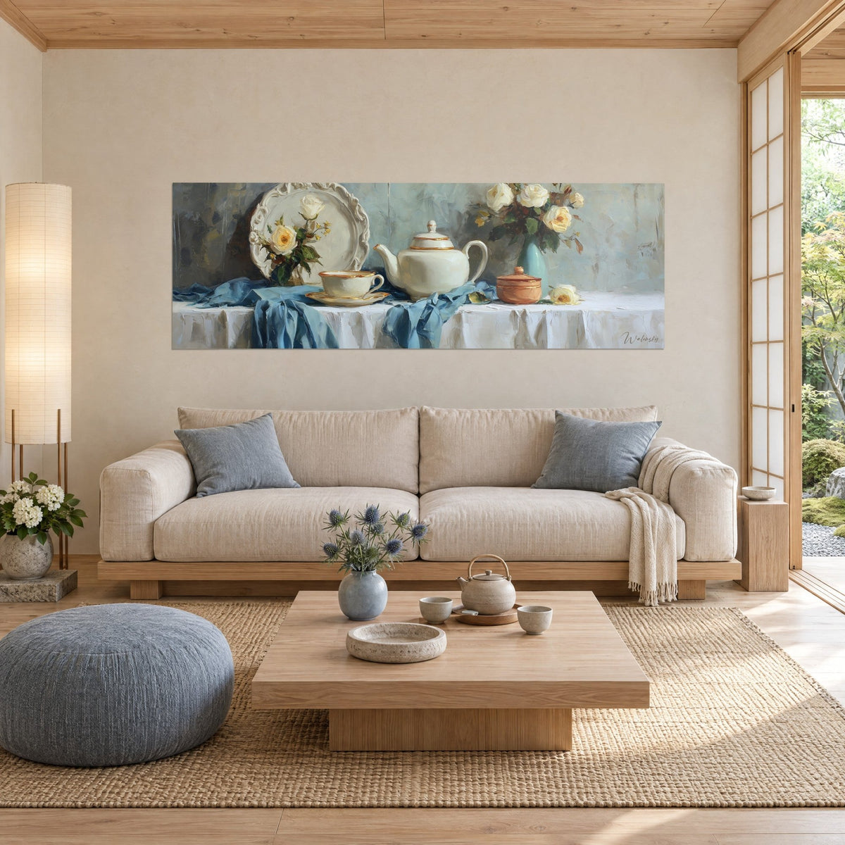 Cuadro tetera de porcelana marfil con filos dorados, rosas amarillas y mantel azul, sobre un sofá en un salón luminoso