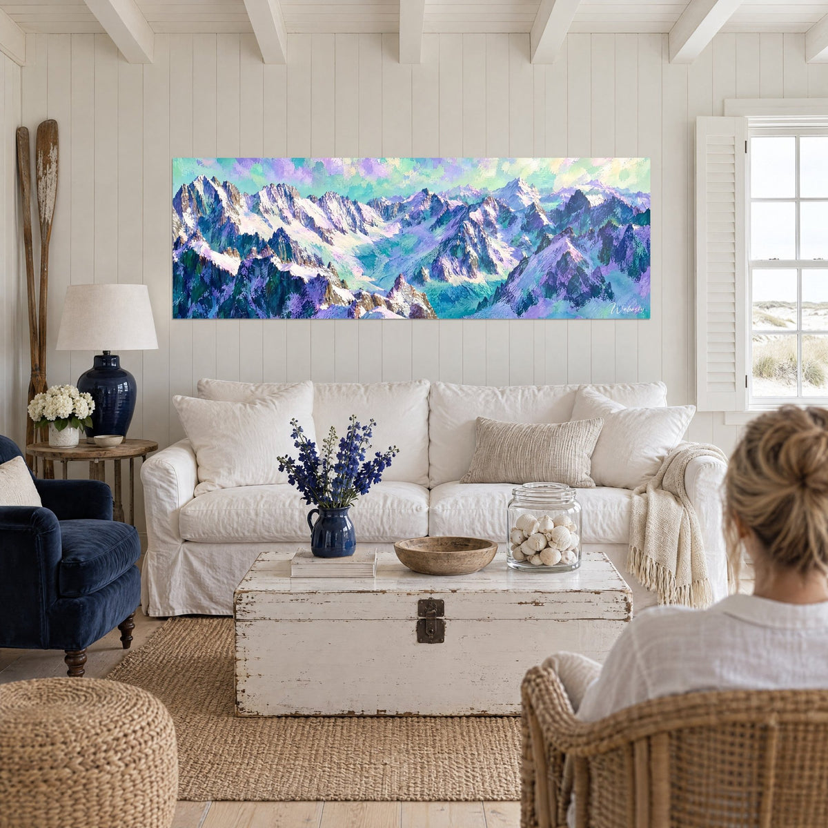 Tableau massif enneigé aux crêtes violettes et turquoise, deux personnes de dos, au-dessus d'un canapé dans un salon lumineux