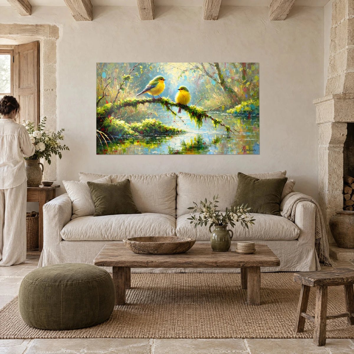 Quadro due cince dal piumaggio giallo limone e verde tenue su un ramo coperto di muschio, una donna di spalle, sopra un divano in un soggiorno luminoso