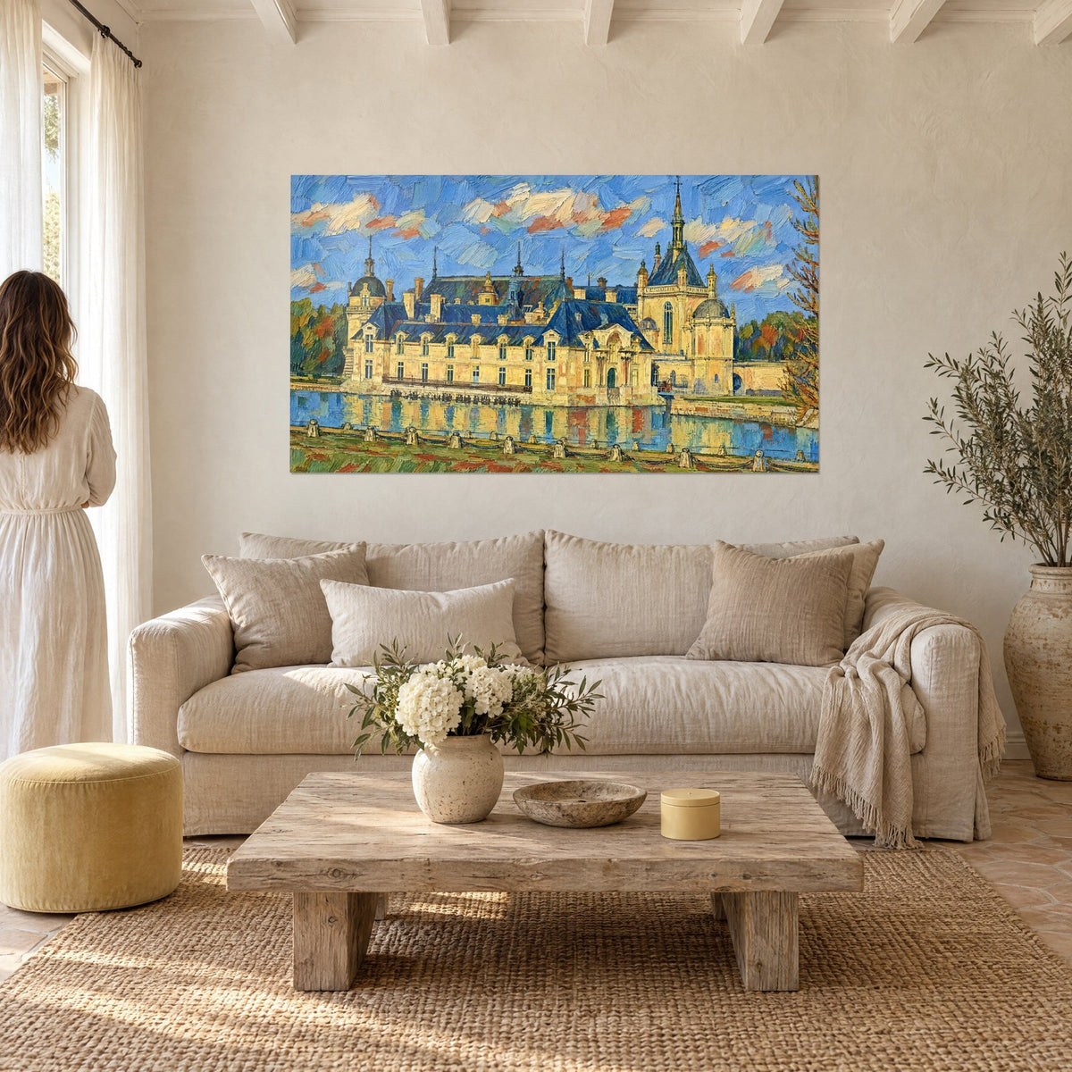 Gemälde Schloss Chantilly mit schieferblauen Dächern und ockerfarbener Fassade, Spiegelungen im Wasser, über einem Sofa in einem hellen Wohnzimmer