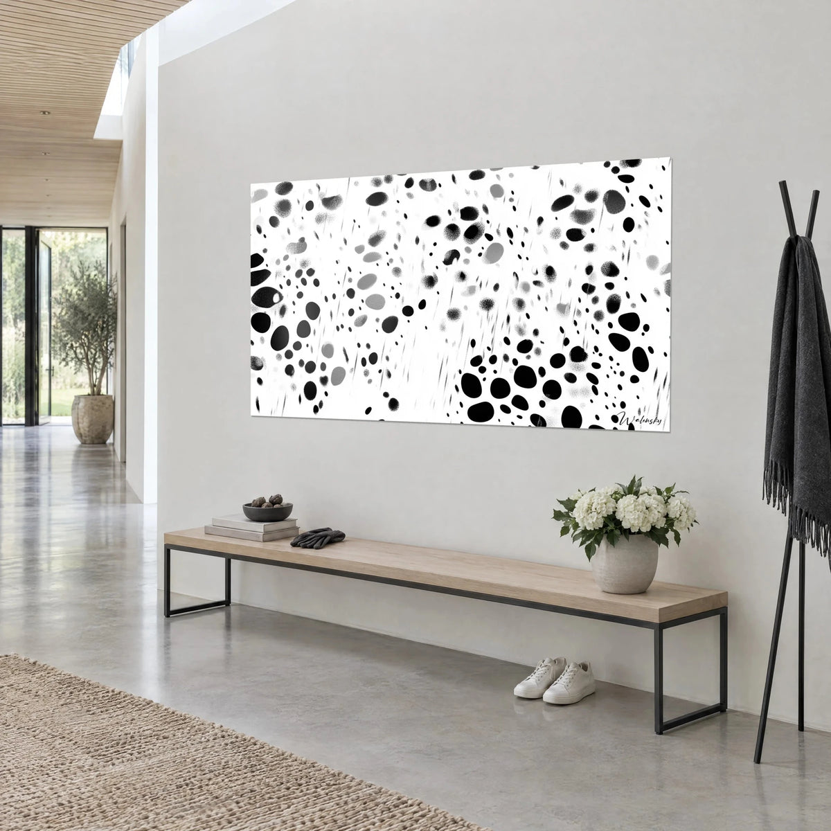 Wall art with a deep black and soft grey speckled pattern, splashes and fine streaks, grey wall, low wooden bench, white flowers