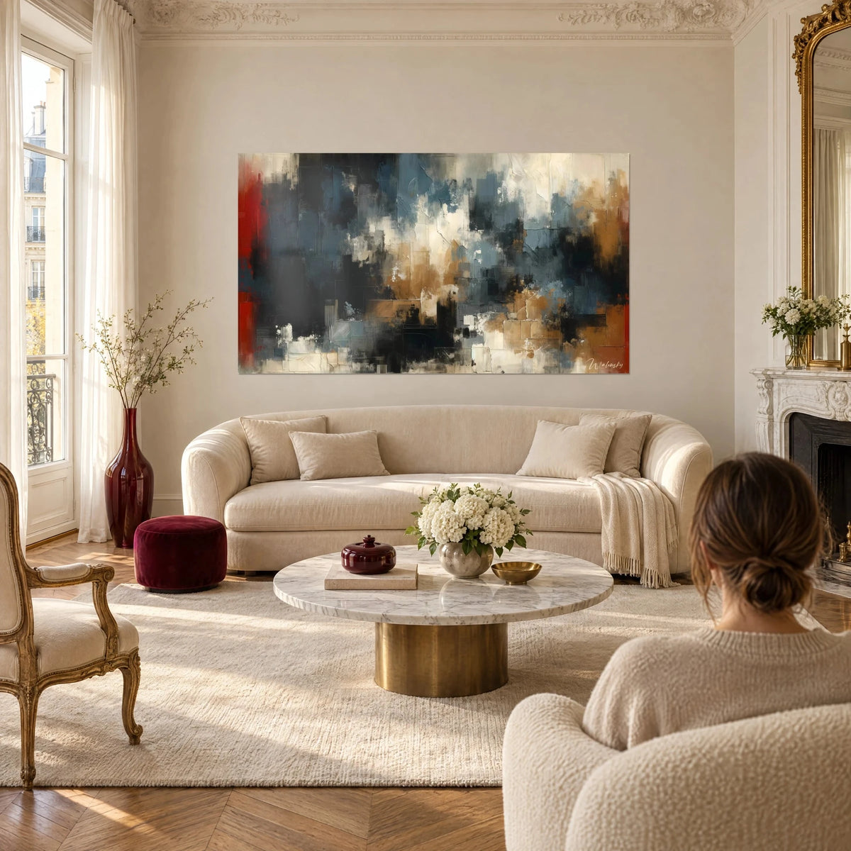 Tableau abstrait aux strates noires et bleu ardoise, éclats crème et ocre, bande rouge, au-dessus d'un canapé dans un salon lumineux