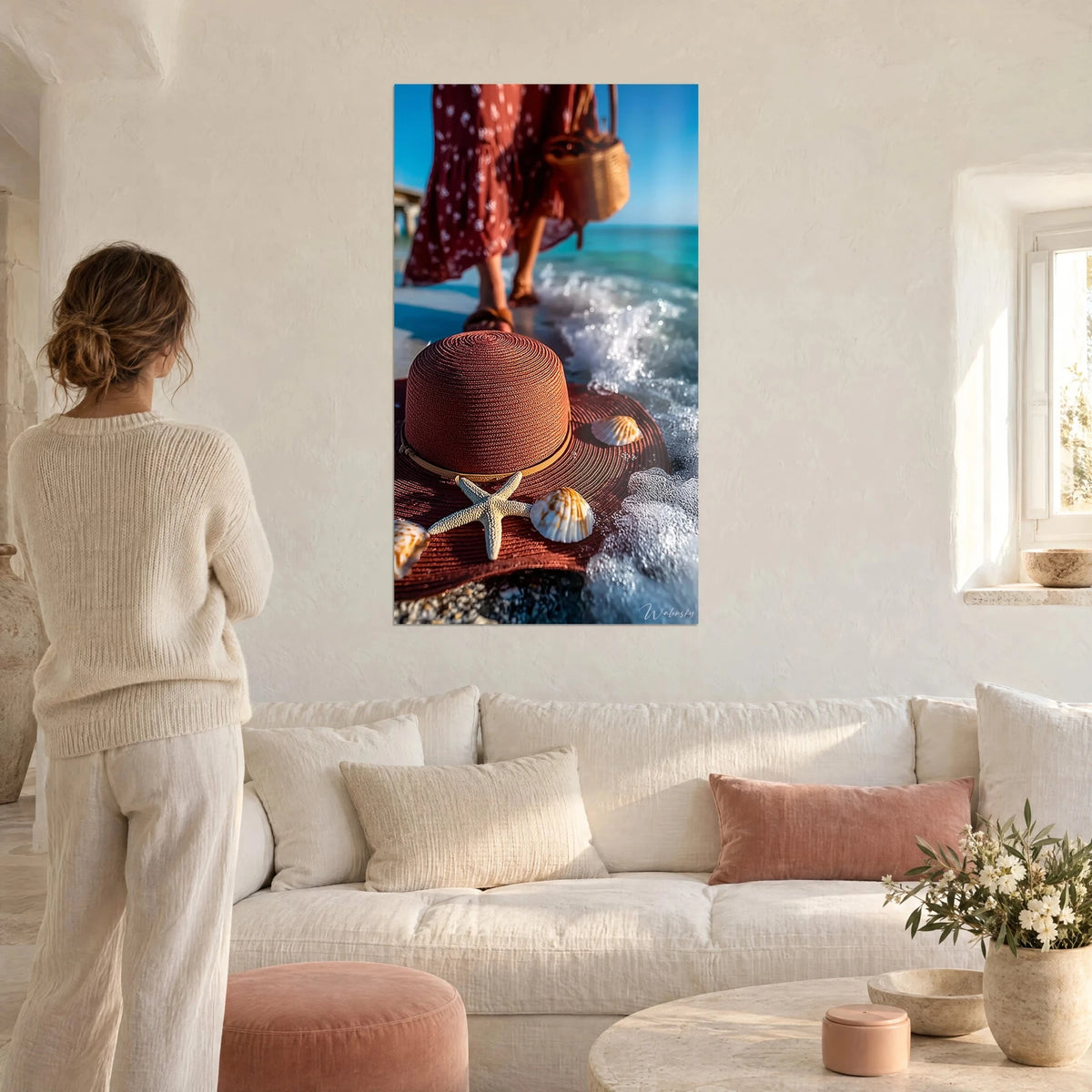 Wall art brick-red straw hat adorned with a starfish, white wall, woman from behind, above a sofa in a bright living room