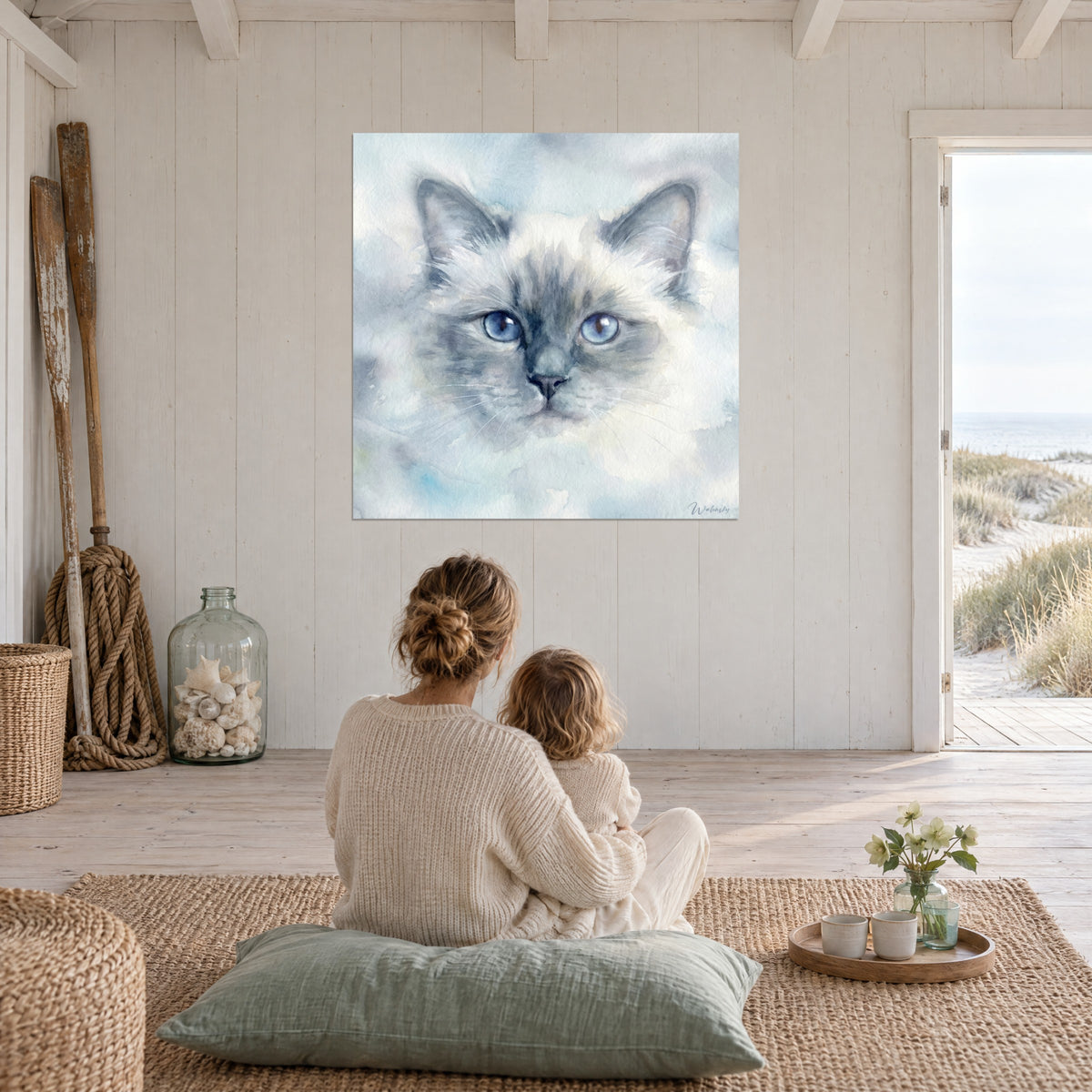 Cuadro mirada azul de gato Birmano, pelaje marfil aéreo y sombras gris azulado, frente a una madre y su hijo sentados en el suelo