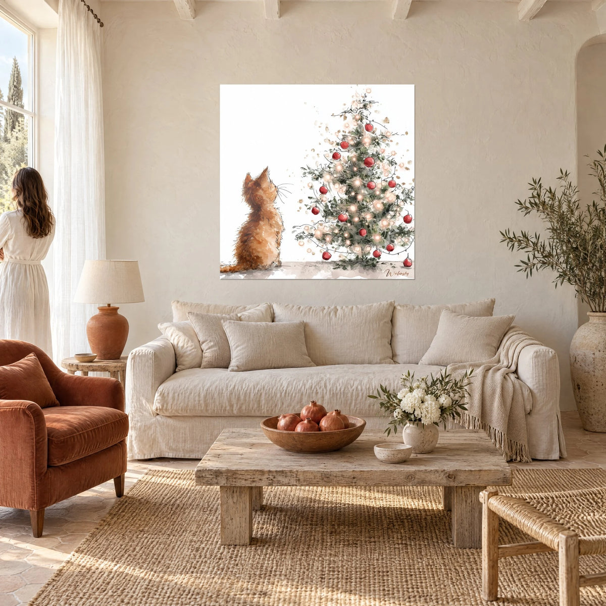 Wall art of a ginger kitten sitting, muzzle raised toward a fir tree with red baubles, white background, above a sofa in a bright living room