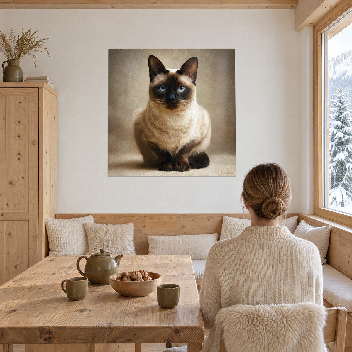 Gemälde Burmakatze sitzt kerzengerade, gletscherblaue Iris und elfenbeinfarbenes Fell, gegenüber einer Frau von hinten in einer Essecke aus hellem Holz