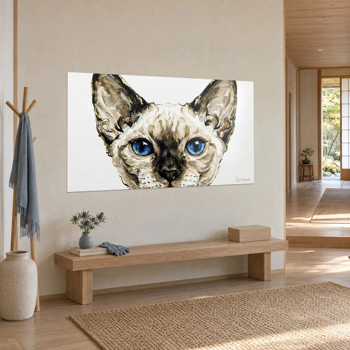 Schilderij donkere snuit van een Siamese kitten, intens blauwe iris en okerkleurige oren omrand met bladgoud, aan beige muur naast een bank van licht hout