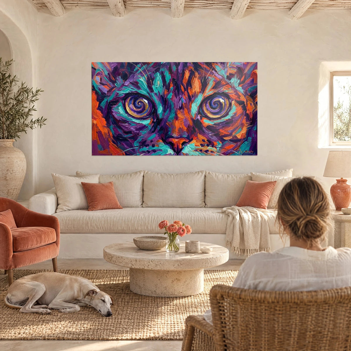 Schilderij Devon rex-kat met paarse spiraalogen, turquoise en oranje vacht, vrouw van achteren, boven een bank in een lichte woonkamer