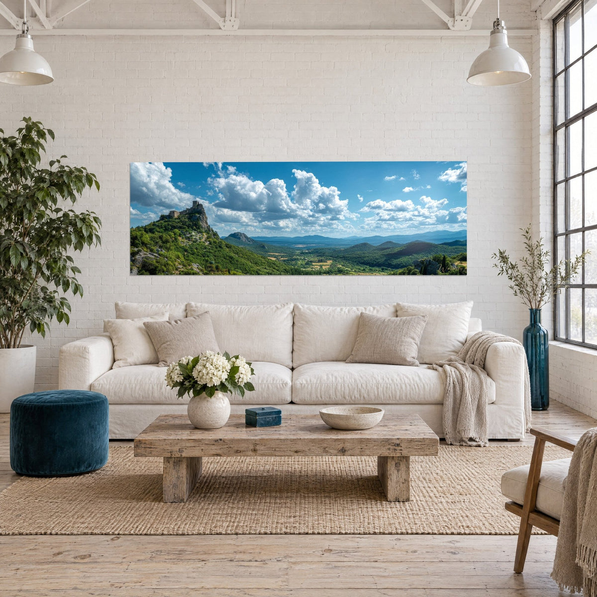 Tableau château en ruines sur son piton rocheux, vallée verte et ciel bleu nuageux, au-dessus d'un canapé dans un salon lumineux