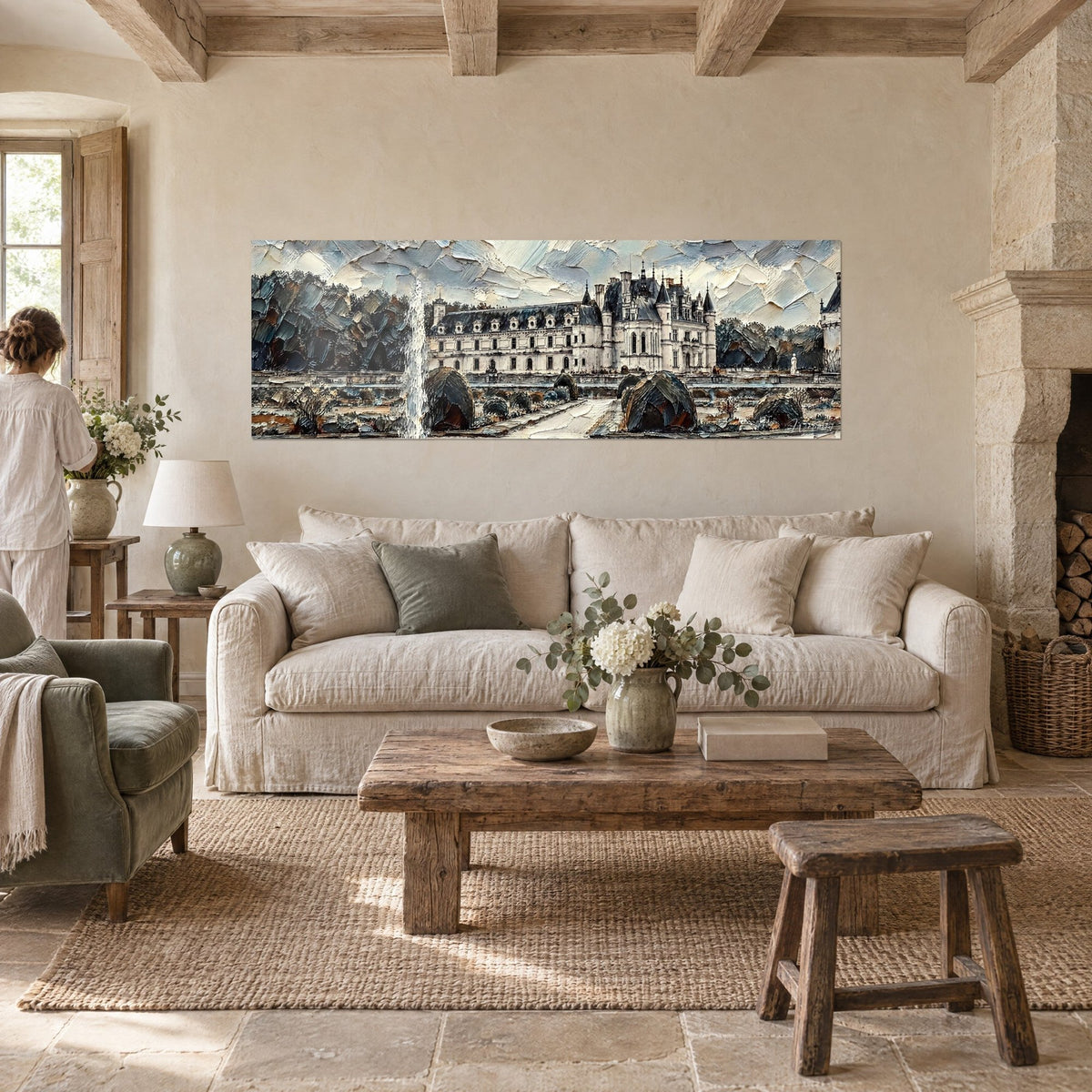 Gemälde Schloss in Weiß mit Schieferdächern, geschnittene Gärten in Grau und Blau, zwei Personen von hinten über einem Sofa in einem hellen Wohnzimmer
