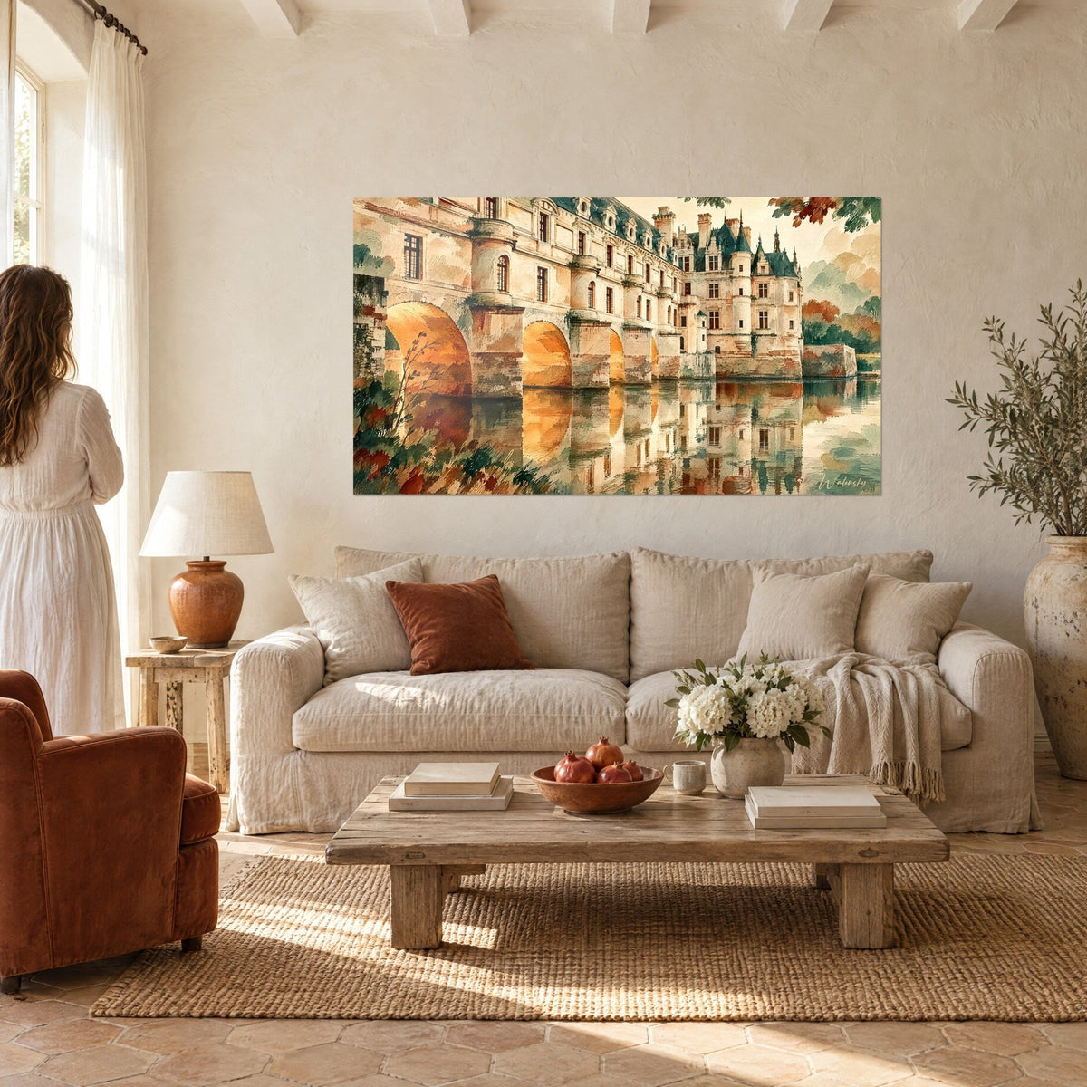 Quadro castello bianco con archi ocra riflessi nell'acqua verde, donna di spalle, sopra un divano in un soggiorno luminoso