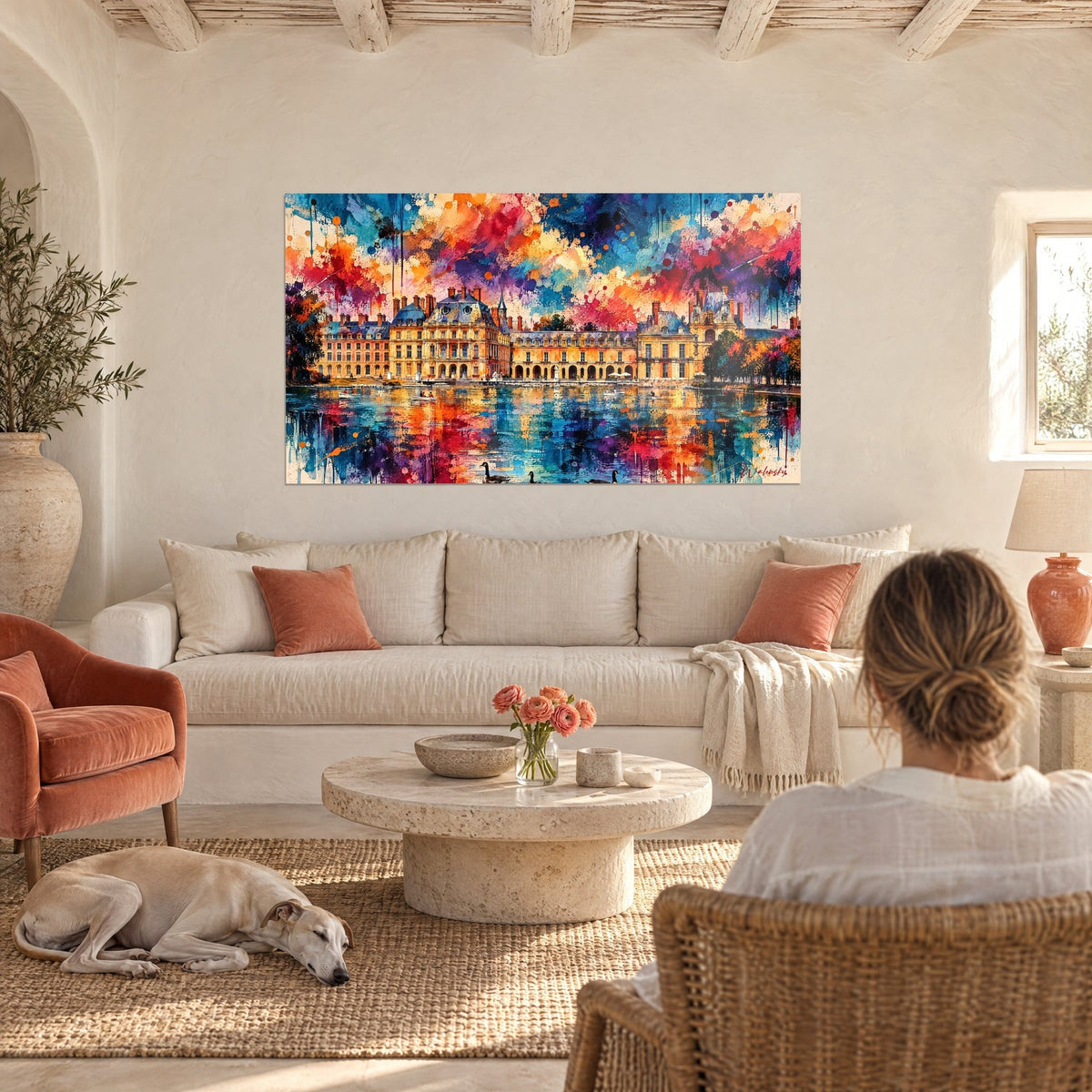 Tableau château doré aux reflets bleus et roses, femme de dos et greyhound couché, au-dessus d'un canapé dans un salon lumineux