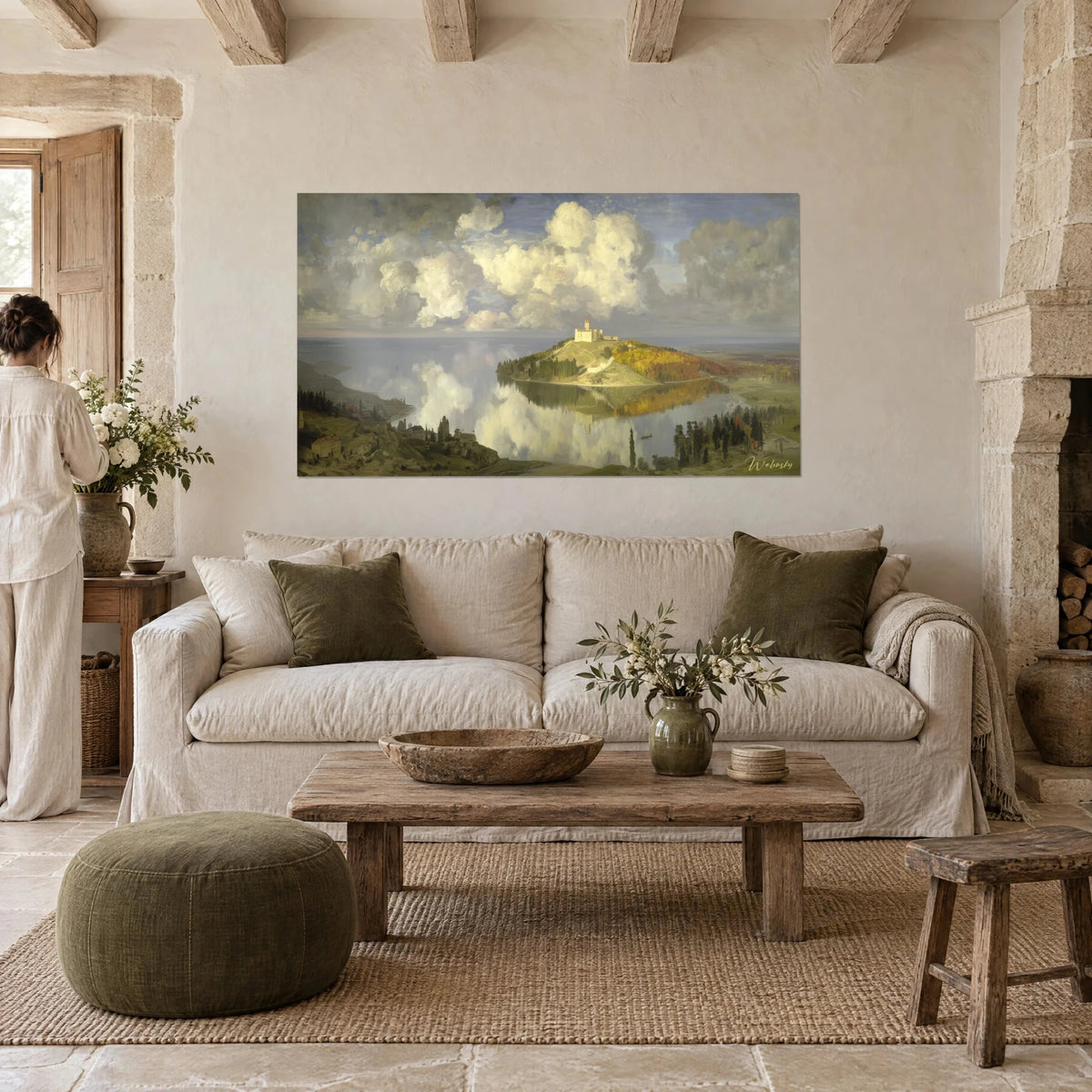 Tableau château blanc perché sur une colline dorée, nuages crème et lac gris, femme de dos au-dessus d'un canapé dans un salon lumineux