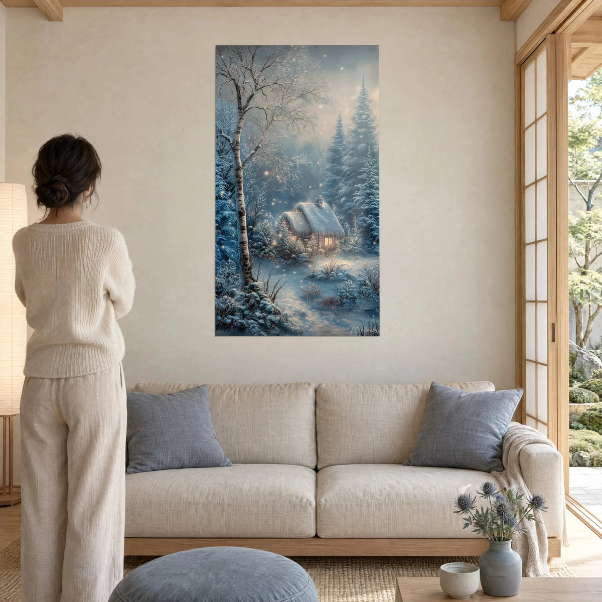 Wall art snowy cottage under frosted birch, white roof and amber windows, glacier blue, above a sofa in a bright living room