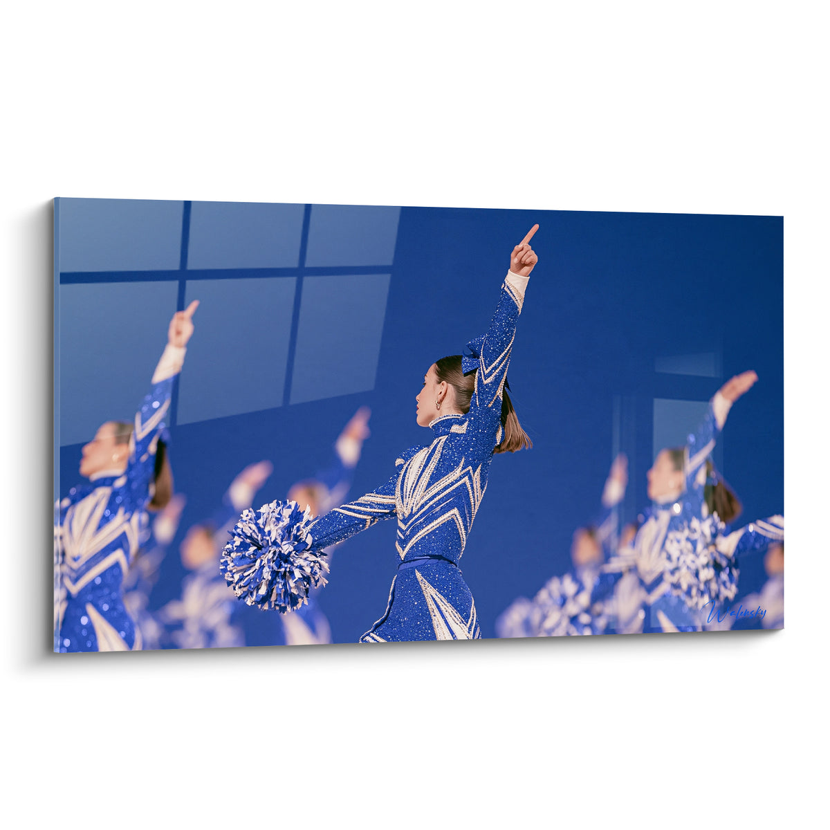 Pom-pom girl en tenue bleu marine et blanche, bras levé, pompon scintillant à la main