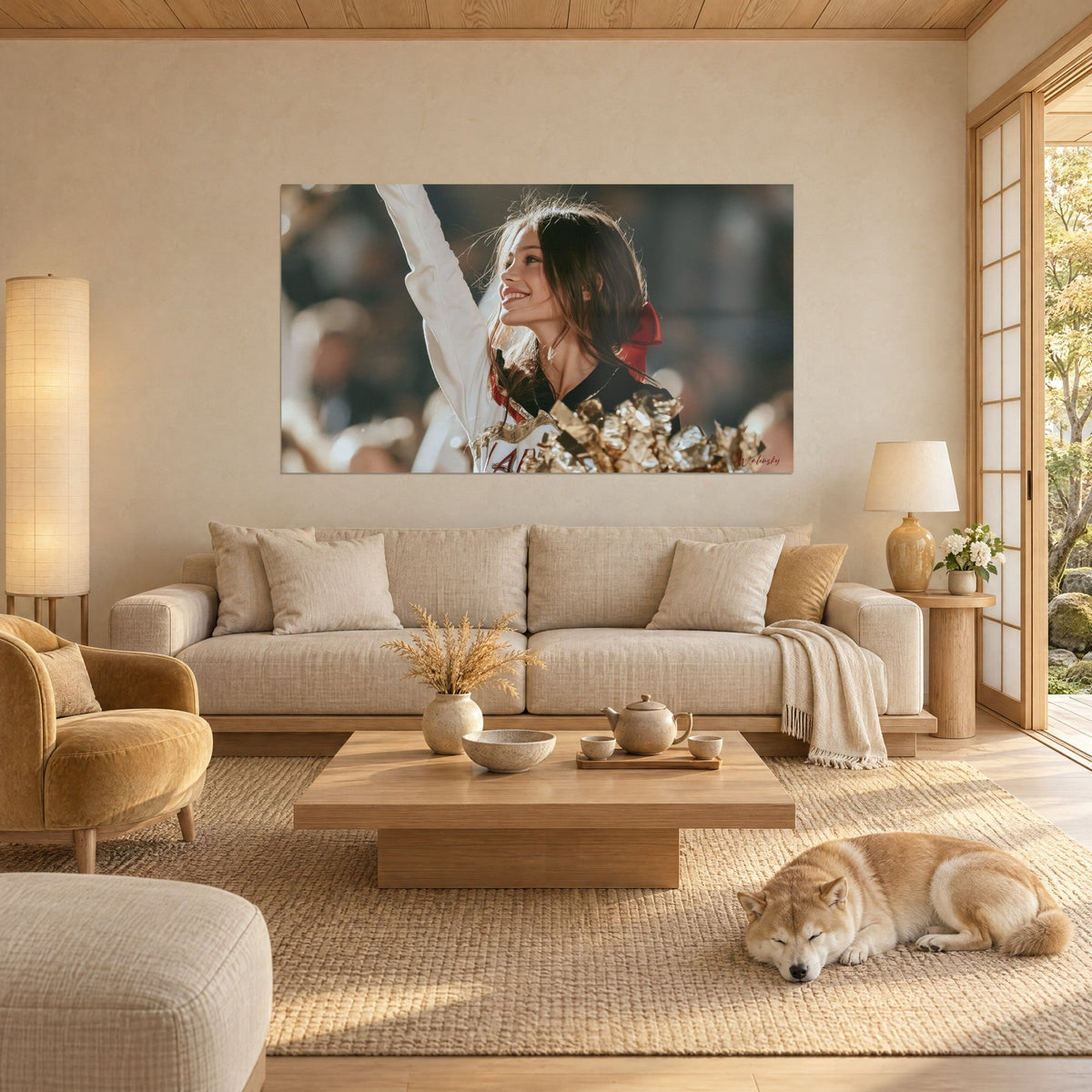 Wall art laughing cheerleader with raised arm, red bow and gold pom-poms, cream wall, sleeping Shiba, above a sofa in a bright living room
