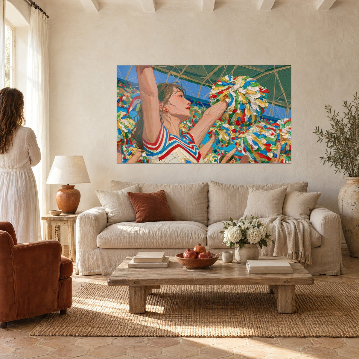 Wall art of a cheerleader in profile, arms raised, red and yellow pom-poms, above a sofa in a bright living room