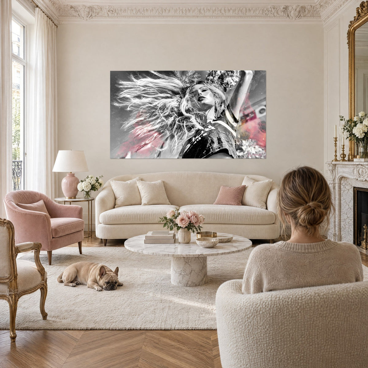 Wall art of a pom-pom girl with long blonde hair flying loose, black and white with powder pink accents, above a sofa in a bright living room