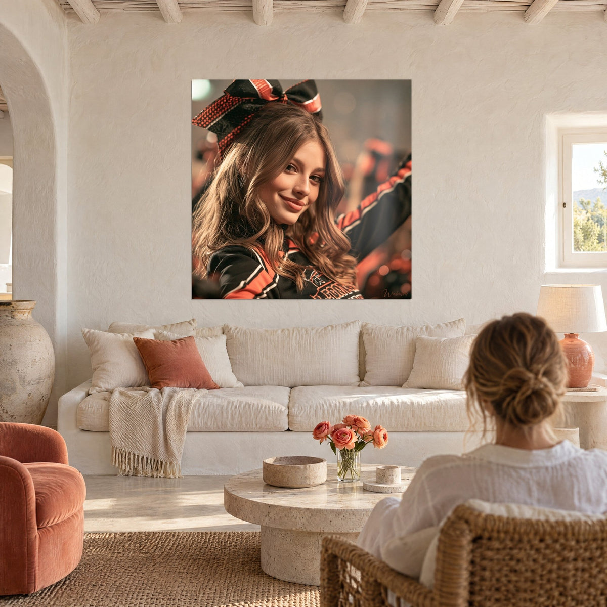 Wall art cheerleader with long chestnut hair and black and orange bow, two people seen from behind, above a sofa in a bright living room