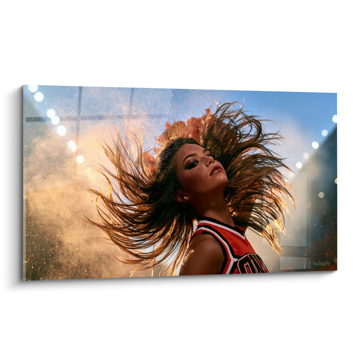 Pom-pom girl aux cheveux bruns et dorés en plein mouvement, maillot rouge et blanc, poussière ambrée