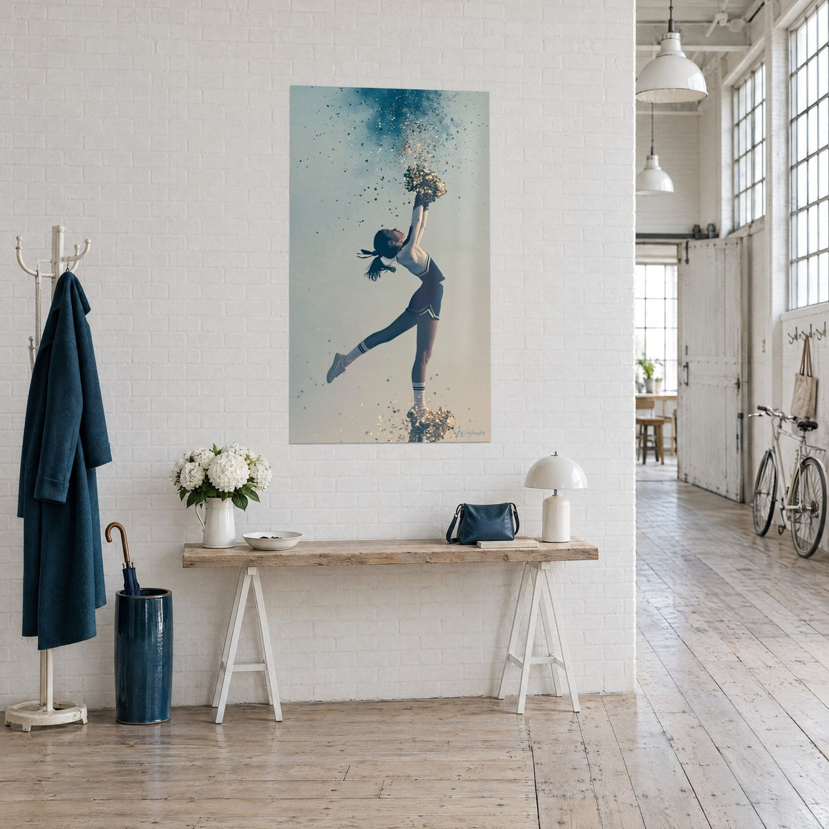 Wall art of a floating cheerleader, golden pom-poms raised, navy skirt, teal sky, on a white brick wall
