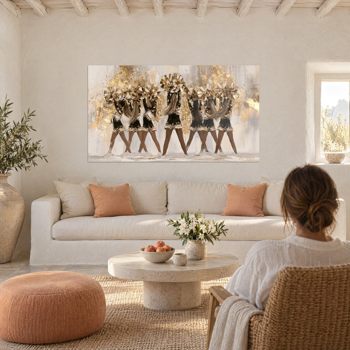 Wall art of gold cheerleaders with sparkling gold pom-poms, black skirts and gold glitter, above a sofa in a bright living room