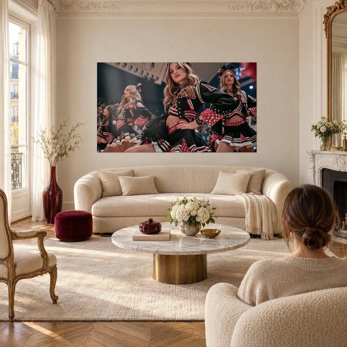 Quadro cheerleader con pon pon in giacca nera con gallone rosse, sguardo sicuro, sopra un divano in un soggiorno luminoso