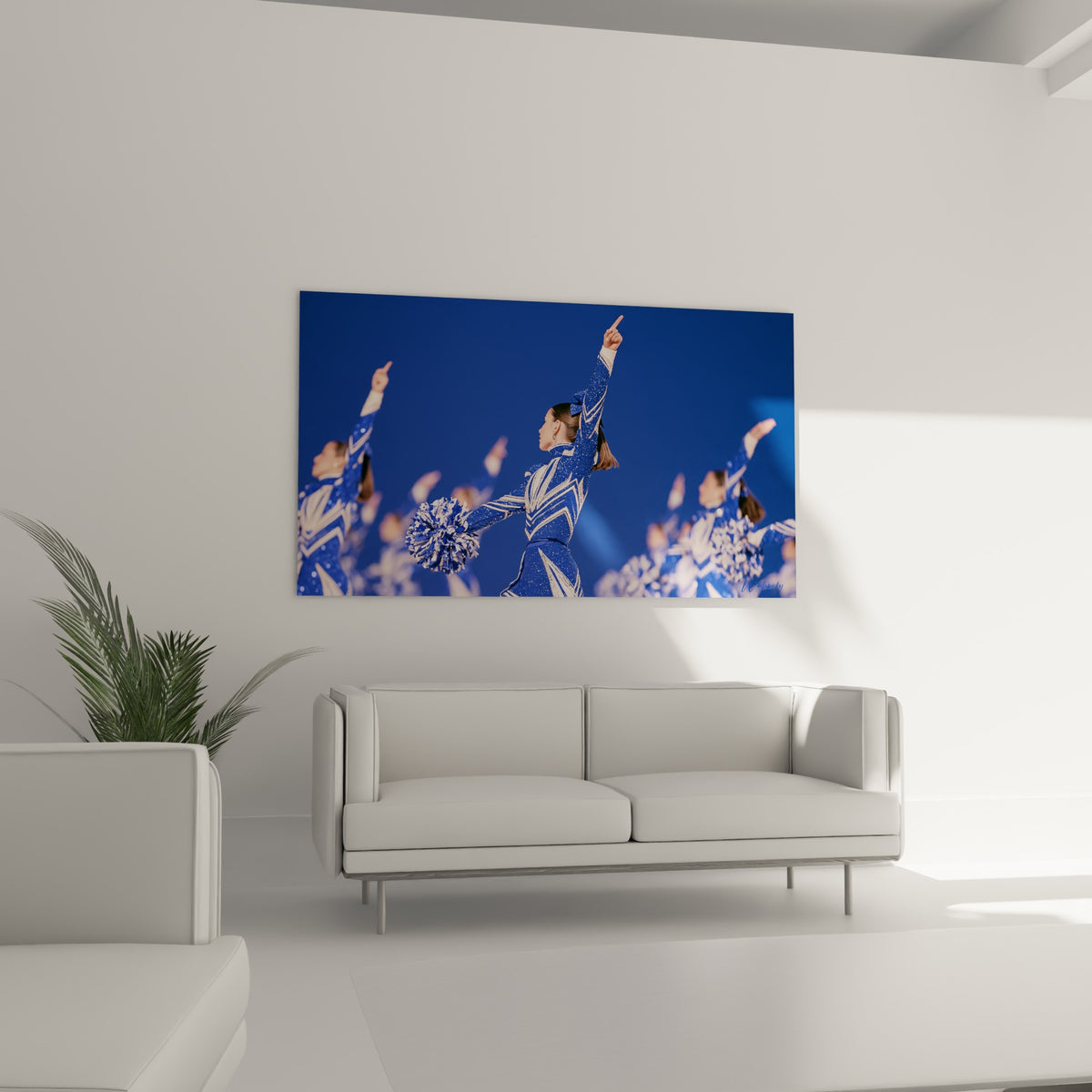 Cheerleader en tenue scintillante bleu marine et blanche, pompon en main, au-dessus d'un canapé dans un salon lumineux