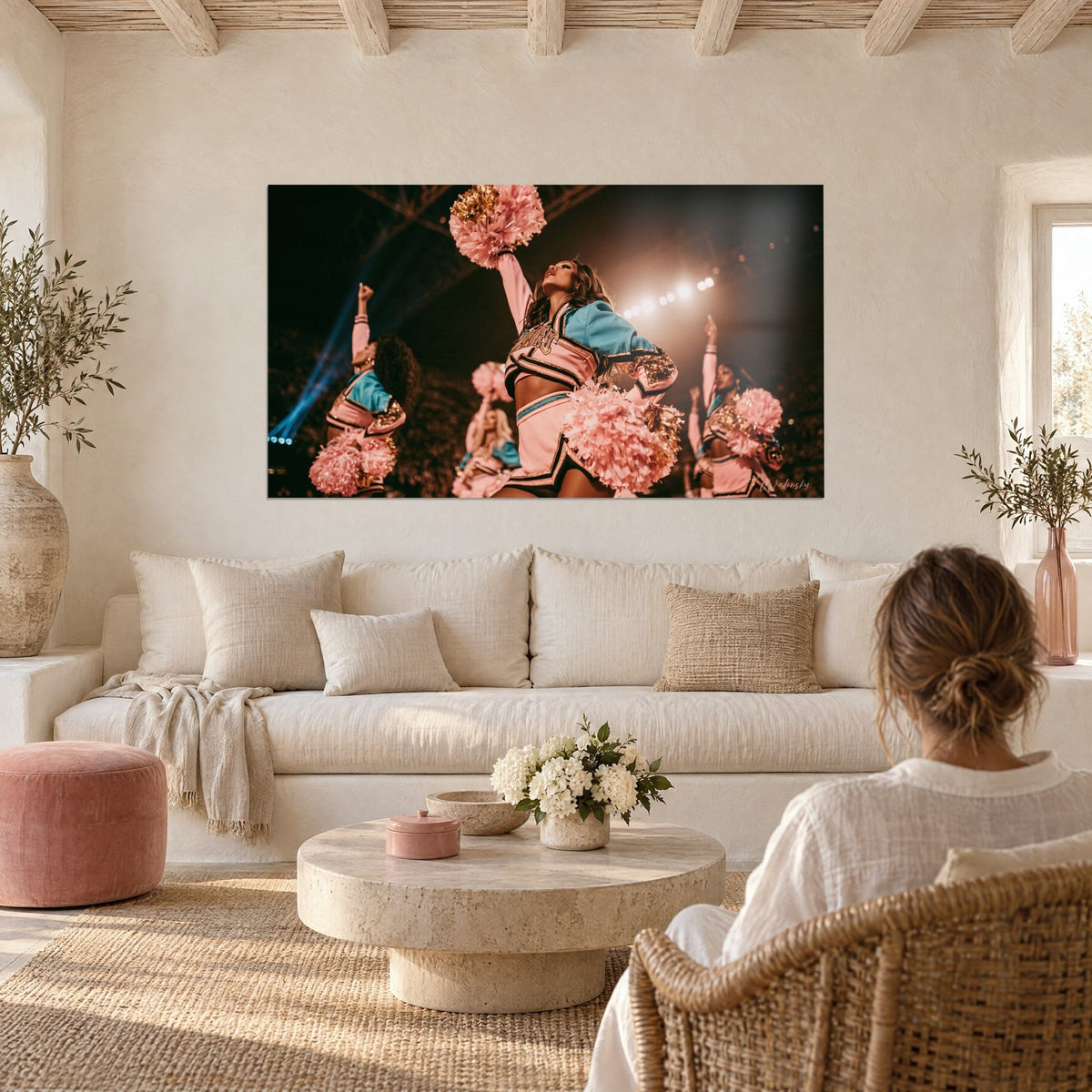 Wall art cheerleader with raised arm, pale pink pom-poms and turquoise jacket under spotlights, above a sofa in a bright living room