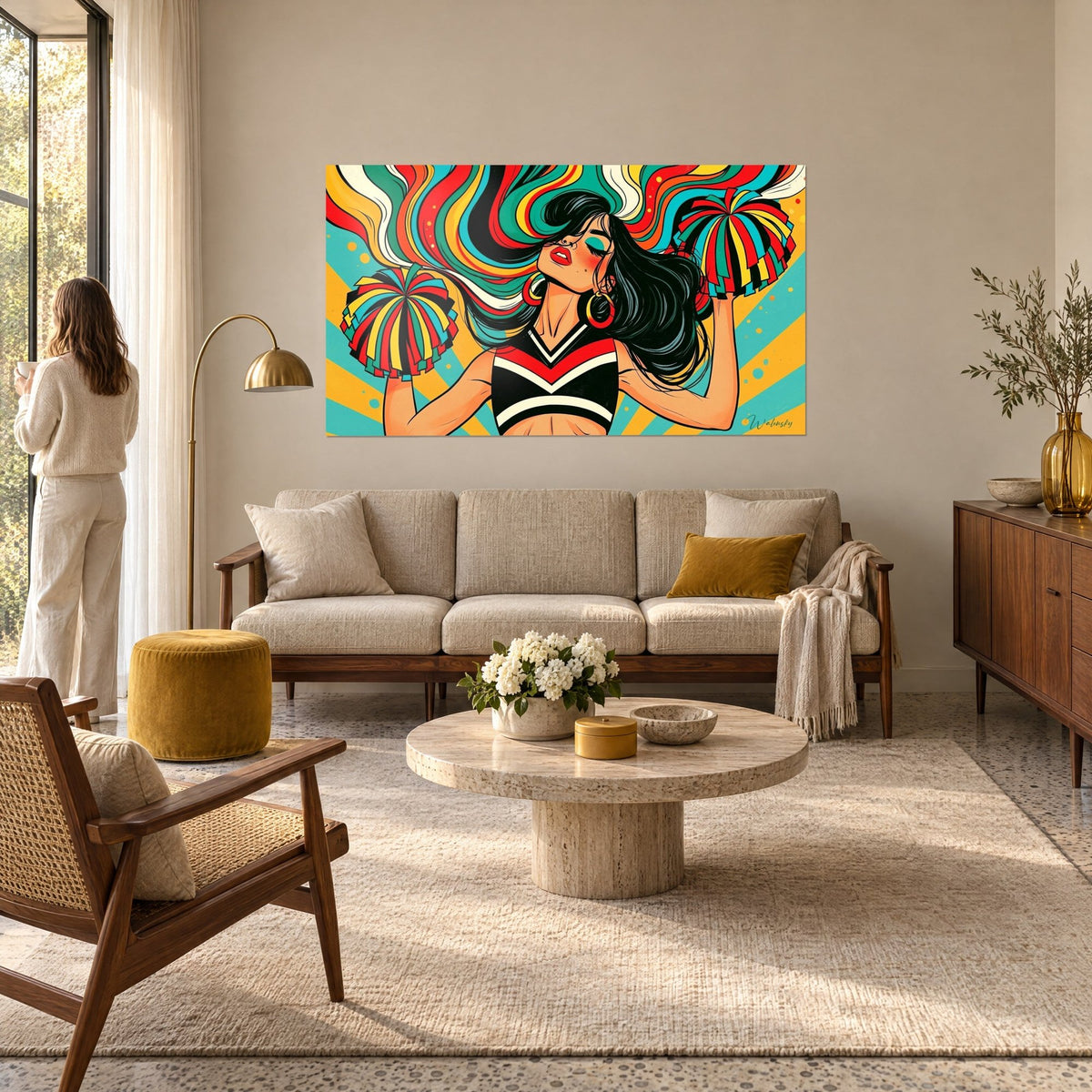 Wall art of a pom-pom girl with wavy multicolored hair, red and turquoise pom-poms, mustard yellow background, above a sofa in a bright living room