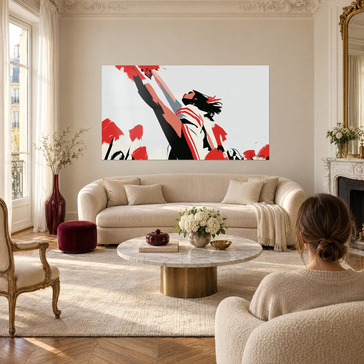 Wall art of a cheerleader in profile, arm outstretched, bright red and black on a light grey background, above a sofa in a bright living room