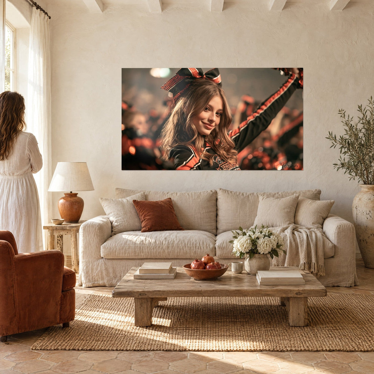 Wall art pom-pom girl with chestnut curls and black and orange bow, knowing smile, above a sofa in a bright living room