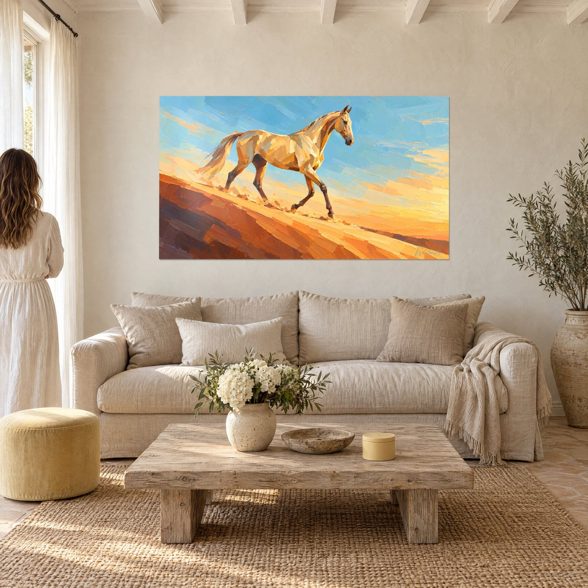 Tableau cheval akhal-teke au pelage crème, ciel bleu et dune ocre, une femme de dos, au-dessus d'un canapé dans un salon lumineux